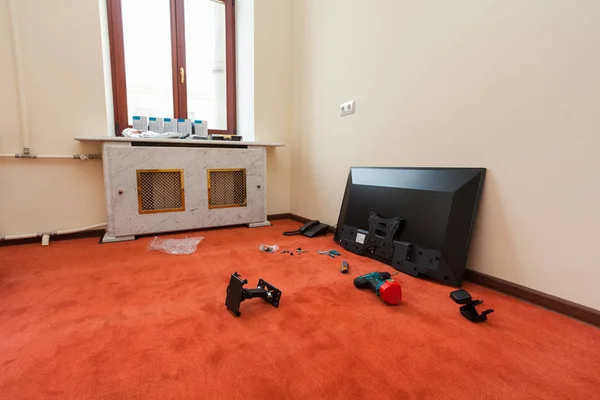Construction materials,  furniture, TV and phone  are on the floor in apartment   of the hotel during under renovation, remodeling and construction.