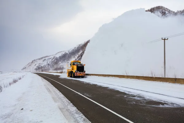 Snowplow truck (Snow removal truck) is removing the snow from the highway during a cold snowstorm winter day