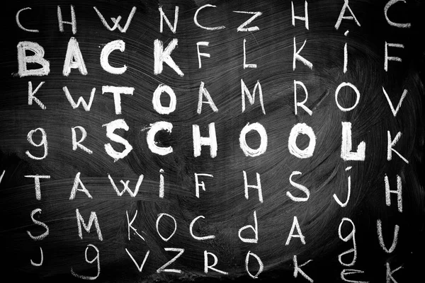 "学校に戻る"英語のアルファベットの他の手紙の中で黒い黒板に白いチョークで書かれたタイトルの学校背景に戻る。ビネット効果 — ストック写真