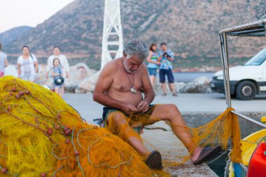 Bali, Island Girit, Yunanistan, - 30 Haziran 2016: yaşlı Yunan balıkçı net yakınındaki balıkçı teknesi Yunanistan Crete adada bulunan iskelede balık onarma.