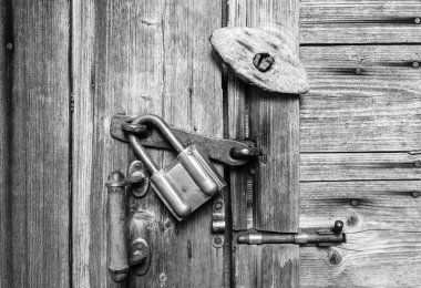 Ahşap kapı kolu, eski asma kilit, eski metal ve ahşap kapı mandalları ile yüzey. Siyah ve beyaz doku.