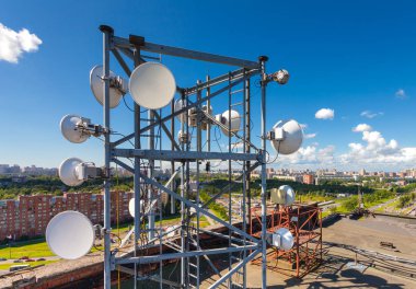 Tv anten, uydu anteni, mikrodalga ve panel antenler mobil operatörleri ile telekomünikasyon kule üzerinde çatı ve şehir manzara arka plan olarak yer almaktadır