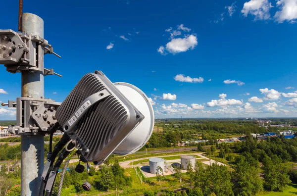 部分电信塔与室外无线通信系统的单元包括微波天线 光缆和电力电缆位于屋顶和城市景观作为背景 基站设备室外单元 — 图库照片