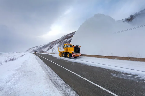 Snowplow truck (Snow removal truck) is removing the snow from the highway during a cold snowstorm winter day