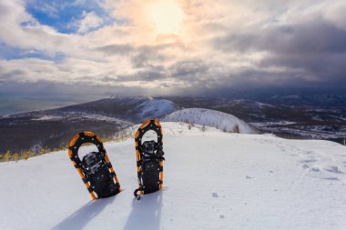 Kar kış dağlar ve gökyüzü bulutlar arka plan ile profesyonel kar ayakkabıları. Snowshoeing.