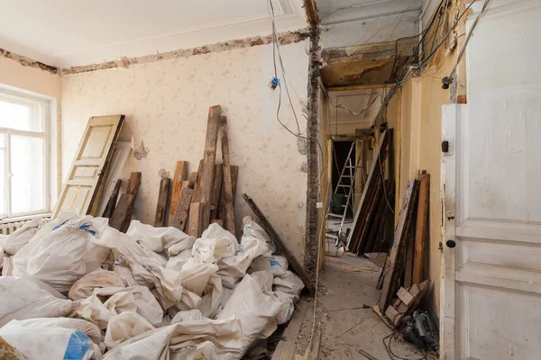 View room of the apartment and retro chandelier during under renovation, remodeling and construction. The process of disassembly old room and packing constraction garbage into the sacs. — Stock Photo, Image