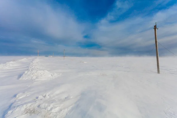 Líneas eléctricas de fase rota en los postes eléctricos en el campo en el invierno durante la tormenta y fuerte viento con nieve. Rusia. Isla Sakhalin — Foto de Stock