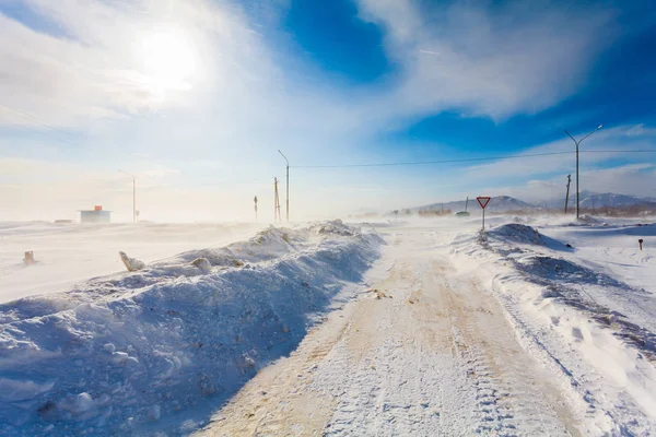Опасная снежная дорога с дорожными знаками для вождения автомобилей и общественного транспорта во время метели или снежной бури с плохой видимостью на дороге в сельской местности . — стоковое фото