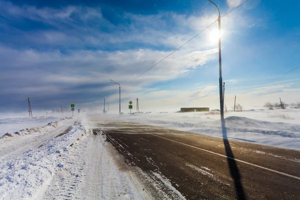 Peligrosa nevada camino vacío con paso de peatones, parada de autobús y señales de tráfico para conducir coches y transporte público durante ventisca o tormenta de nieve . — Foto de Stock