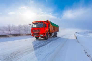 Hareket Bulanıklığı kış yolu üzerinde bir yük taşıyan kırmızı bir damperli kamyon