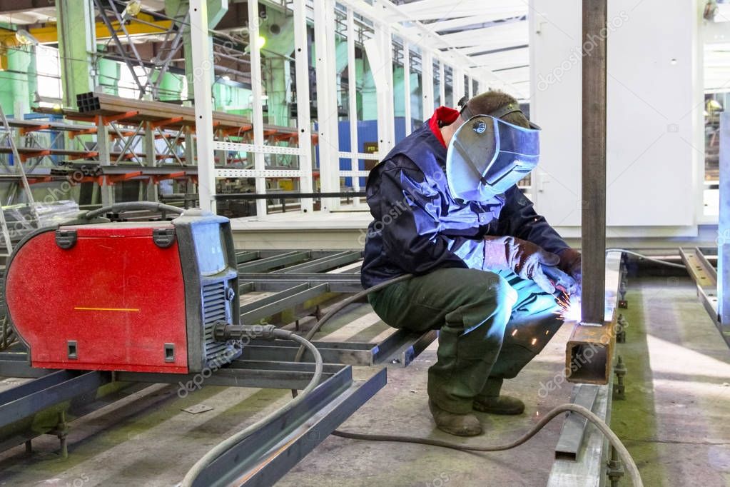 Welder is working at the factory and welding a metal construction