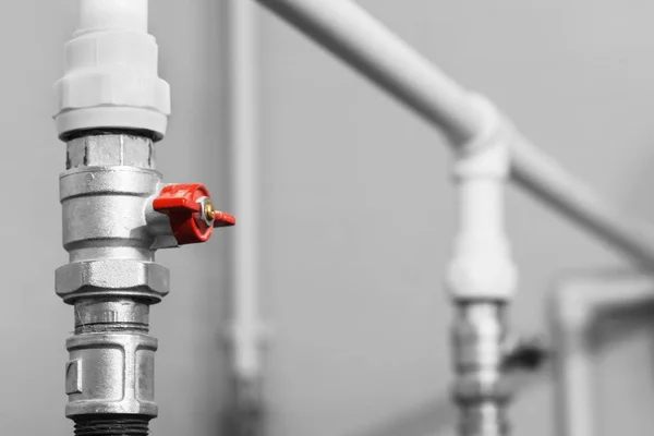 Černobílý obrázek z vodovodní ventil s červenými kohoutek na plastové vodovodní potrubí vodovodní systém. Detail. — Stock fotografie