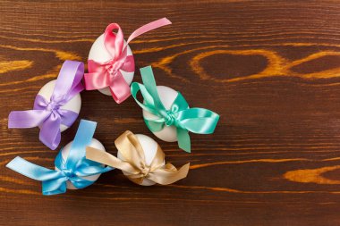 Paskalya yumurtaları ahşap arka plan üzerinde renkli şerit yay bağladılar