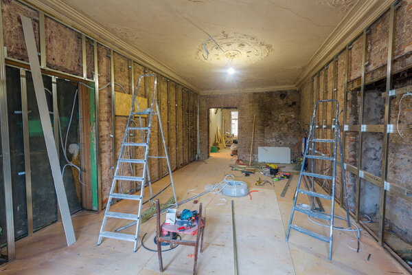 Рабочий процесс установки металлических рам для гипсокартона (гипсокартона) для изготовления гипсокартонных стен с лестницами и инструментами в квартире строится, реконструируется, обновляется, расширяется, реставрируется и реконструируется
