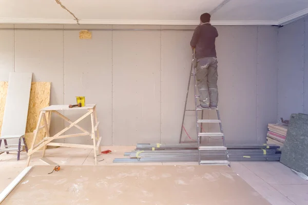 工人从梯子上工作 并安装石膏墙 用于在建 修复和重建的公寓里 — 图库照片