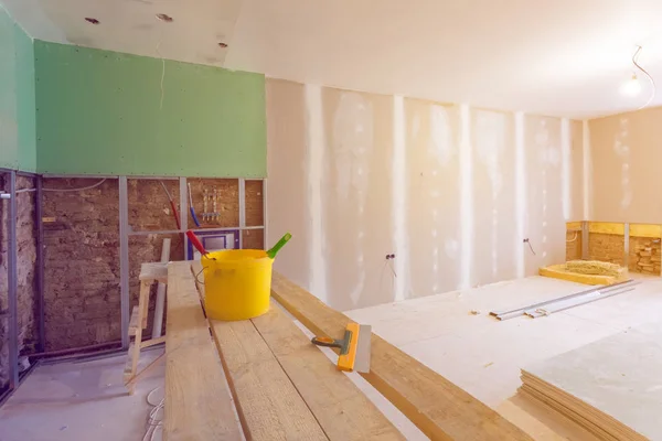 Puttees mes, gele emmer met lijm en lijm rollen op het houten bord in kamer is onder constructie, verbouwing, renovatie, uitbreiding, herstel en wederopbouw. — Stockfoto