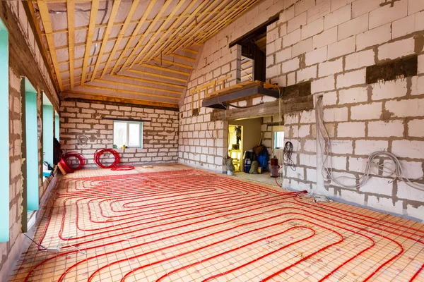 Pipefitter installing system of heating or underfloor heating installation. Water floor heating system interior. Plumbing pipes in apartment during under renovation, remodeling and construction