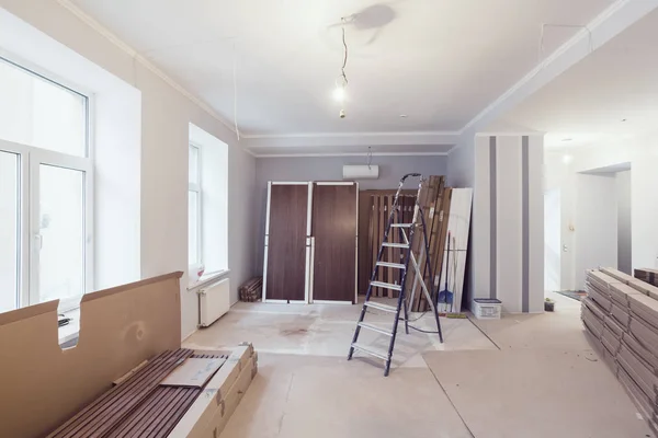 Interieur appartement tijdens bouw, verbouwing, renovatie, uitbreiding, herstel en wederopbouw - ladder en bouwmaterialen in de kamer — Stockfoto