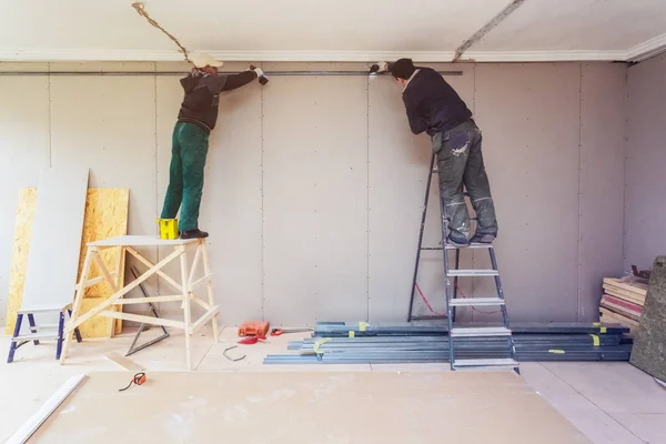 Werknemers installeert gipsplaten gipsplaat voor gips wanden in het appartement is in aanbouw, verbouwing, renovatie, uitbreiding, herstel en wederopbouw. — Stockfoto