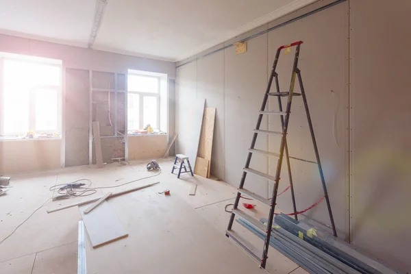 Interieur appartement tijdens bouw, verbouwing, renovatie, uitbreiding, herstel en wederopbouw - ladder en bouwmaterialen in de kamer — Stockfoto