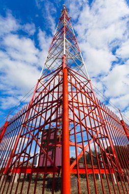 Telekomünikasyon kule ile paneli antenler ve radyo antenleri ve çanak antenler mobil iletişim 2g, 3g, 4g, 5g kule mavi gökyüzü bulutlar ile etrafında kırmızı çit ile için