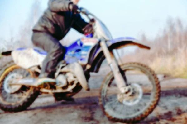 Pilota di motocross offuscata che accelera in pista sterrata sulla gara di motocross di montagna in pista sterrata durante il giorno. Sfondo sfocato con effetto bokeh . — Foto Stock