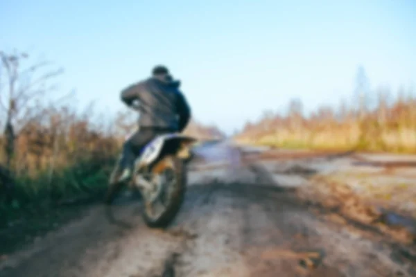 模糊越野摩托车车手加速在泥土轨道上的山地越野摩托车比赛的污垢轨道在白天的时间。散景效果模糊背景. — 图库照片