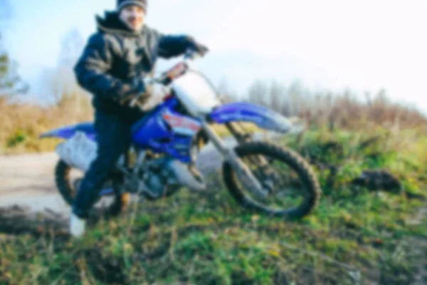 Blurred motocross racer accelerating in dirt track on the mountain motocross race in dirt track in day time. Blurred background with bokeh effect. — Stock Photo, Image