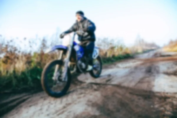 Rozmazané motokrosový jezdec zrychluje v prašné cestě na horu motokrosovém závodě v prašné cestě v denní době. S efektem bokeh rozostřeného pozadí. — Stock fotografie