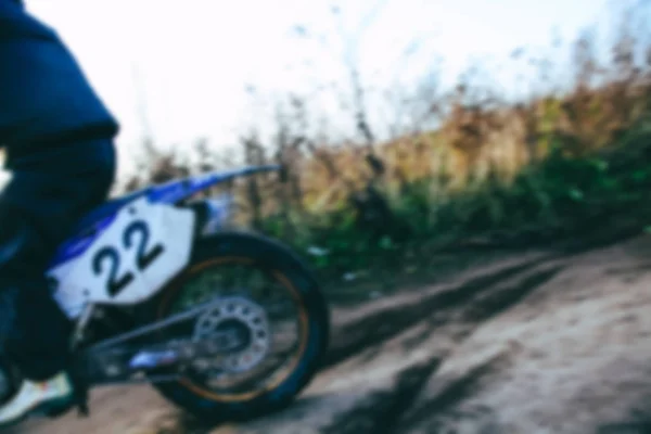 Blurred motocross racer accelerating in dirt track on the mountain motocross race in dirt track in day time. Blurred background with bokeh effect. — Stock Photo, Image
