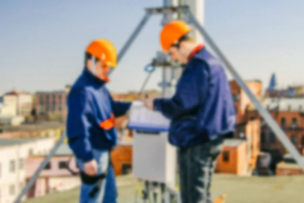 Escaladores industriales profesionales borrosos en casco y uniformes aprenden proyecto para la instalación de equipos de comunicación —  Fotos de Stock