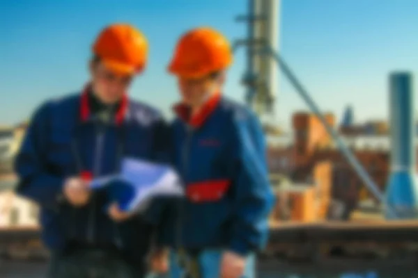 Blurred professional industrial climbers in helmet and uniform learns project for instaling communication equipment