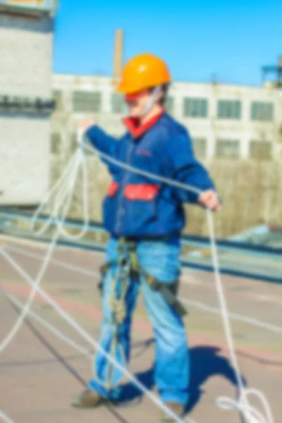 Blurred professional industrial climber in helmet and uniform works at height for instaling communication equipment and antenna.