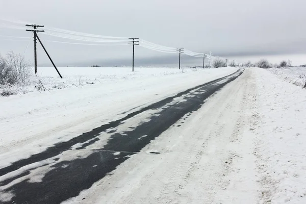 Líneas eléctricas con escarcha en los postes eléctricos de madera en el campo en la carretera de invierno e invierno — Foto de Stock