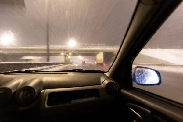 Изображение с размытым движением. Автомобили быстро ездят по зимнему скоростному шоссе или шоссе с дорожным освещением в снежную бурю в сумерках, когда идет снег с дождём. Мбаппе вождения в — стоковое фото