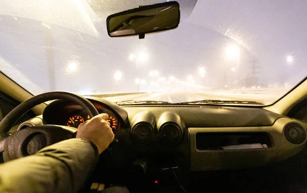 Человек водит машину на зимней скорости во время снежной бури в сумерках, когда идет снег с дождем. Концепция вождения в опасных условиях с плохой видимостью в зимний период . — стоковое фото