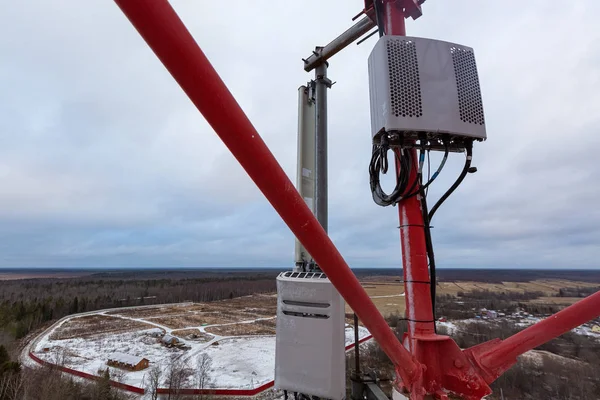 Top of red telecommunication tower with vertical panel antenna and remote radio unit, power and optic cables in winter day. — Stock Photo, Image