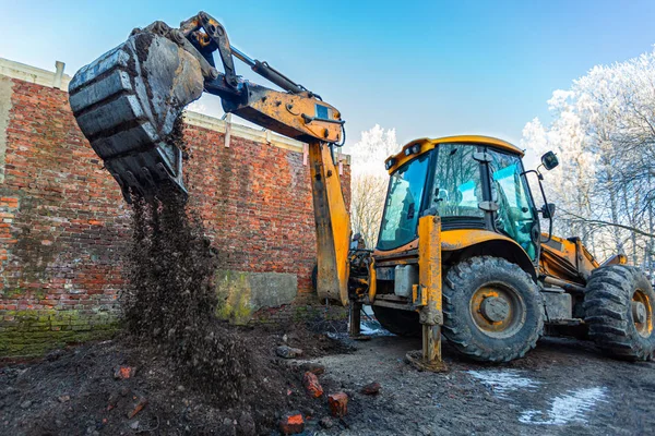 The modern excavator performs excavation work on the construction site. Front view of a digger bucket of digging ground as a part of industry machinery — Stock Photo, Image
