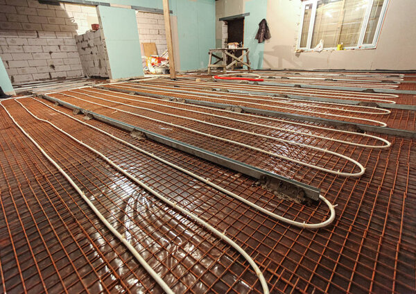 Pipefitter installing system of heating or underfloor heating installation. Water floor heating system interior. Plumbing pipes in apartment during under construction, remodeling, renovation, extensio