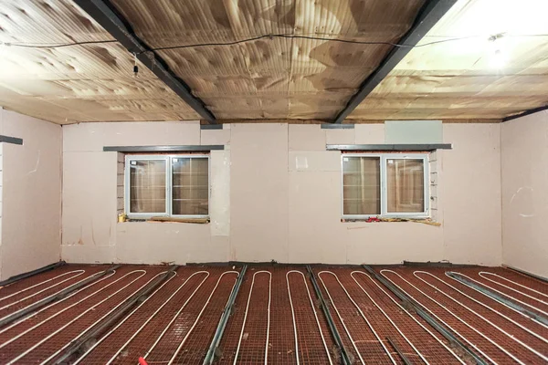Pipefitter installing system of heating or underfloor heating installation. Water floor heating system interior. Plumbing pipes in apartment during under construction, remodeling, renovation, extensio