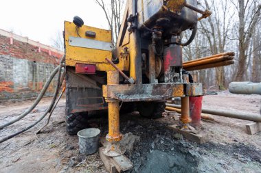 İnşaat alanında büyük tekerlekleri olan eski kamyona hidrolik yeraltı suyu sondaj makinesi yerleştirildi. Yeraltı kuyusu sondajı..
