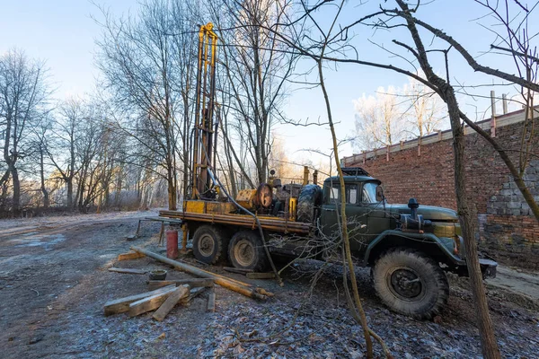 İnşaat alanında büyük tekerlekleri olan eski kamyona hidrolik yeraltı suyu sondaj makinesi yerleştirildi. Yeraltı kuyusu sondajı..