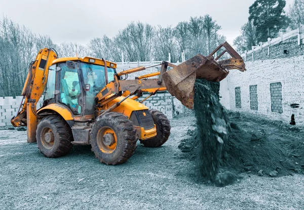 The modern excavator performs excavation work on the construction site. Front view of a digger bucket of digging ground as a part of industry machinery.