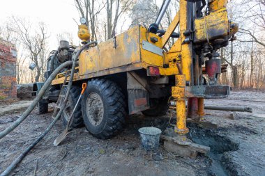 İnşaat alanında büyük tekerlekleri olan eski kamyona hidrolik yeraltı suyu sondaj makinesi yerleştirildi. Yeraltı kuyusu sondajı.