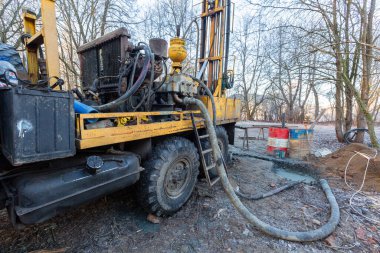 İnşaat alanında büyük tekerlekleri olan eski kamyona hidrolik yeraltı suyu sondaj makinesi yerleştirildi. Yeraltı kuyusu sondajı.