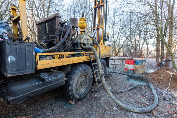 Hydraulic ground water hole drilling machine installed on the old truck with big wheels on the construction site. Groundwater well drilling