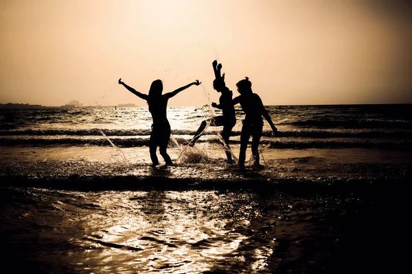 Silhouetten von Frauen, die im Wasser spielen — Stockfoto