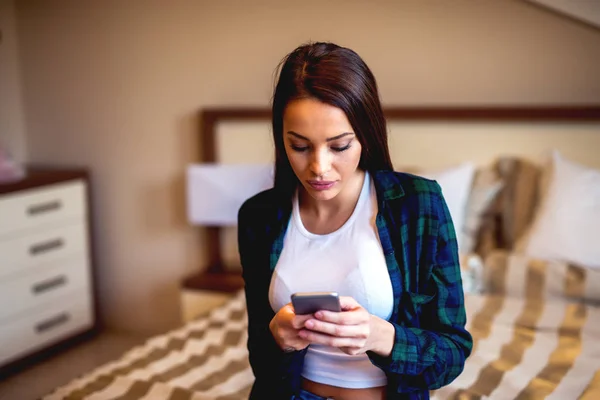 Woman using smartphone in bedroom — Stock Photo, Image