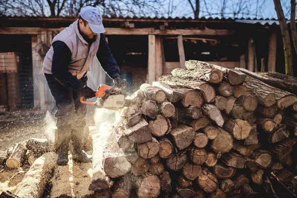 Hombre cortando madera con motosierra — Foto de Stock