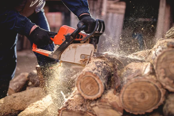 Мужчина рубит дрова бензопилой — стоковое фото